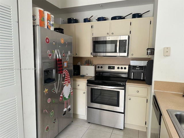 kitchen featuring cream cabinets, stainless steel appliances, light tile patterned floors, and sink