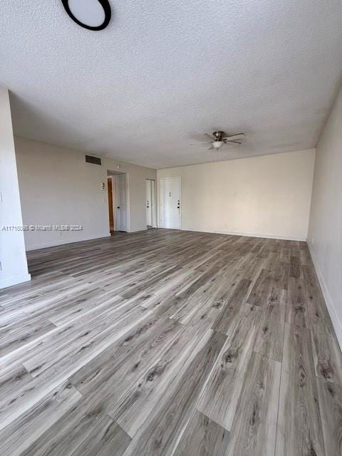 unfurnished living room featuring ceiling fan, light hardwood / wood-style floors, and a textured ceiling