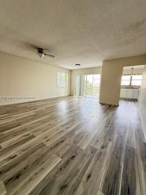 empty room with ceiling fan, dark hardwood / wood-style flooring, and a textured ceiling