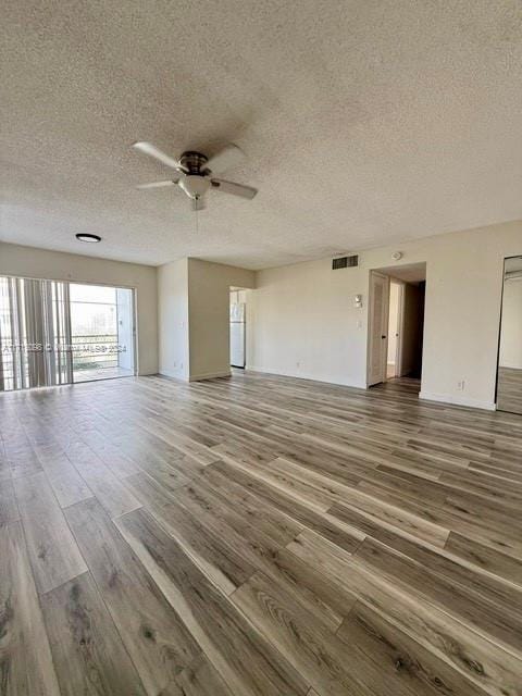 unfurnished living room featuring hardwood / wood-style flooring, ceiling fan, and a textured ceiling