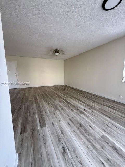 empty room featuring hardwood / wood-style floors, a textured ceiling, and ceiling fan