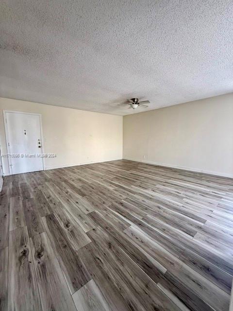 unfurnished room featuring hardwood / wood-style flooring, ceiling fan, and a textured ceiling