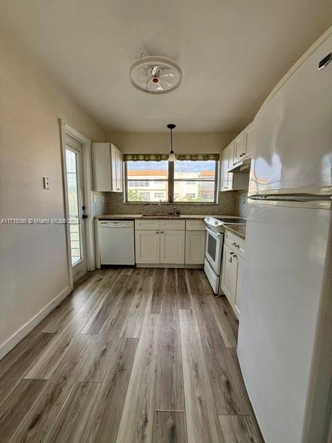 kitchen featuring a wealth of natural light, white cabinetry, white appliances, and light wood-type flooring