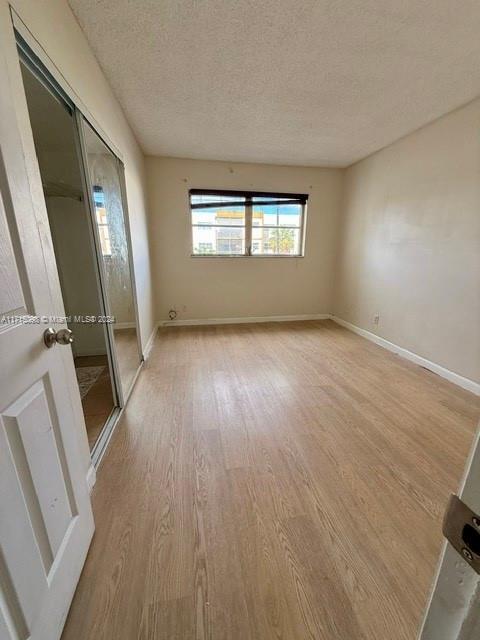 spare room featuring light wood-type flooring and a textured ceiling