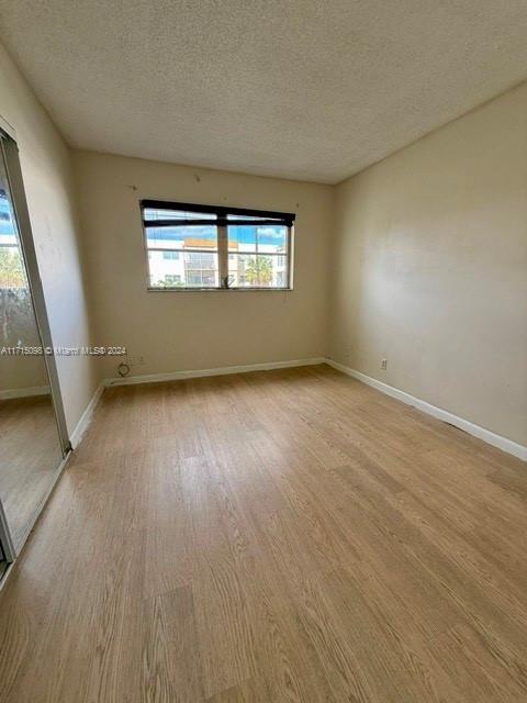 unfurnished room featuring light hardwood / wood-style floors and a textured ceiling