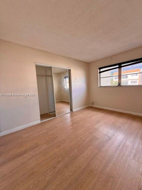 unfurnished bedroom with a closet, a textured ceiling, and light hardwood / wood-style flooring