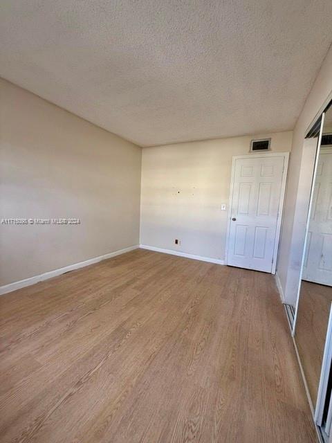 spare room with a textured ceiling and light hardwood / wood-style flooring