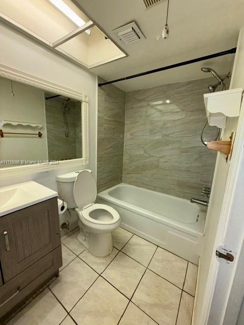 full bathroom with tile patterned floors, vanity, tiled shower / bath combo, and toilet