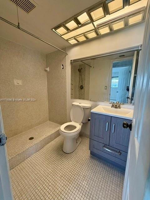 bathroom featuring tile patterned floors, vanity, toilet, and a tile shower