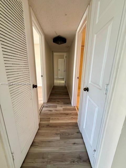 corridor with light hardwood / wood-style floors and a textured ceiling