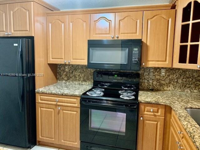 kitchen featuring light stone countertops, tasteful backsplash, and black appliances