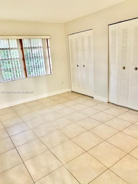 unfurnished bedroom featuring multiple closets and light tile patterned floors