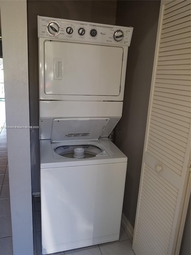 laundry room with light tile patterned floors and stacked washer / dryer