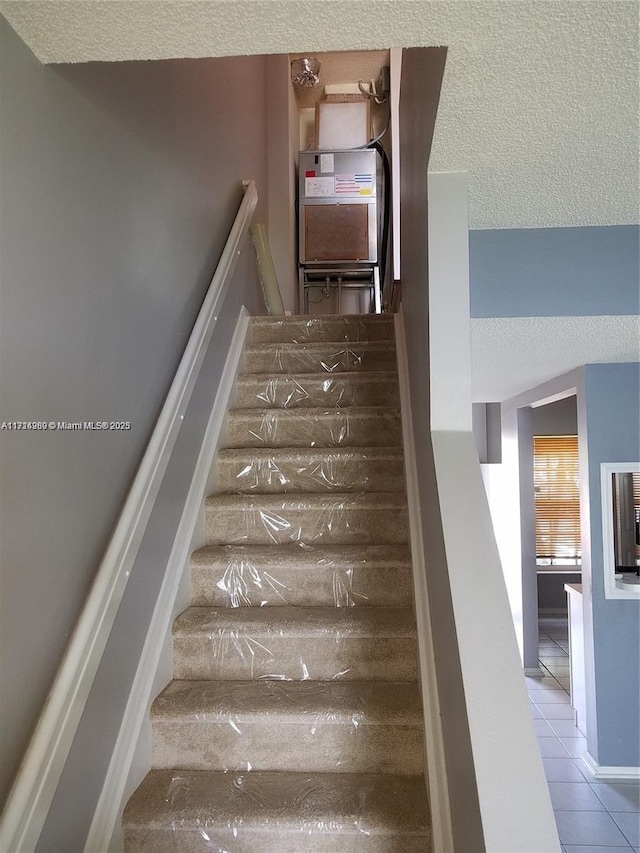 stairway featuring a textured ceiling and tile patterned floors