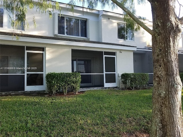 back of property with a yard and a sunroom