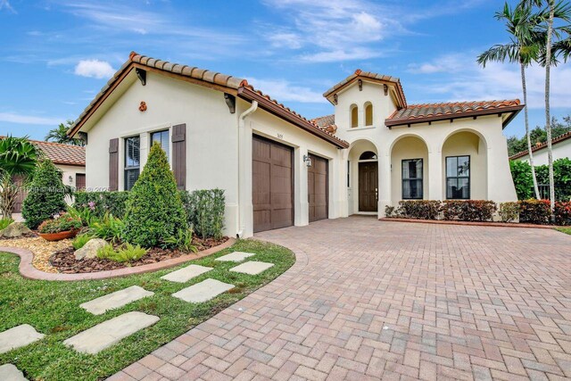 mediterranean / spanish-style house featuring a front yard and a garage