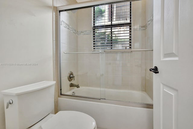 bathroom featuring bath / shower combo with glass door and toilet