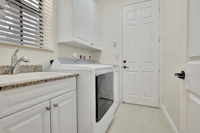 clothes washing area featuring separate washer and dryer, sink, and cabinets