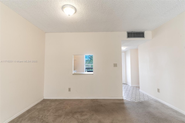 spare room featuring carpet flooring and a textured ceiling