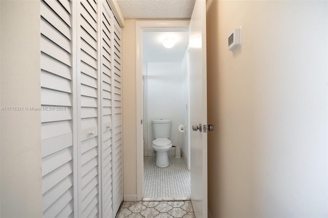 bathroom with tile patterned flooring, toilet, and a textured ceiling