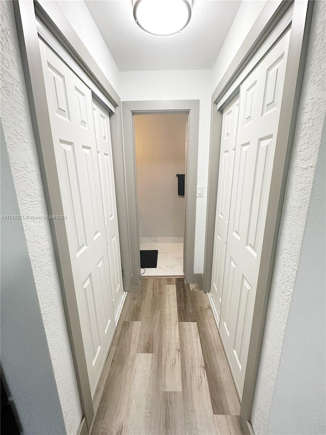 hall featuring a textured ceiling and light hardwood / wood-style floors