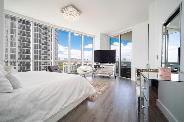 bedroom featuring a chandelier, expansive windows, and dark wood-type flooring