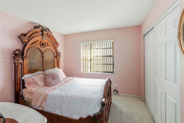 bedroom with light colored carpet, a textured ceiling, and a closet