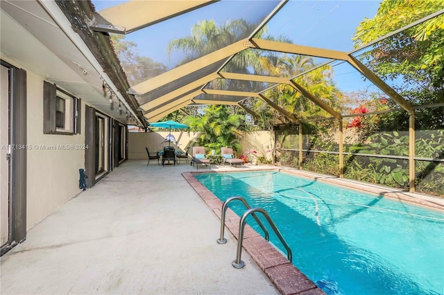 view of pool with glass enclosure and a patio area