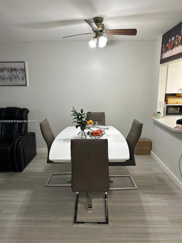 dining room with ceiling fan, baseboards, and wood finished floors