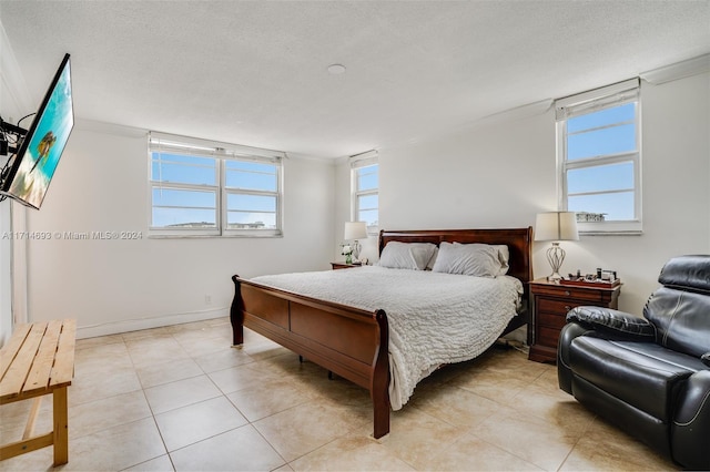 bedroom with crown molding, light tile patterned floors, and a textured ceiling