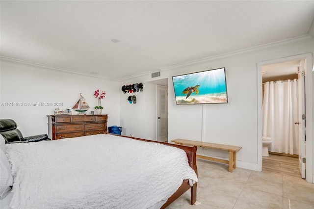 bedroom featuring ensuite bath, light tile patterned floors, and ornamental molding