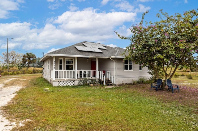 bungalow featuring covered porch, solar panels, and a front yard