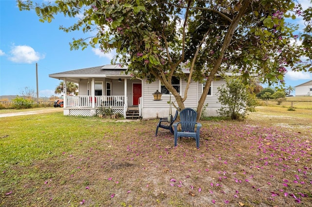 view of front facade with a front lawn, solar panels, and covered porch