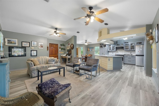 living room with lofted ceiling, sink, and light wood-type flooring