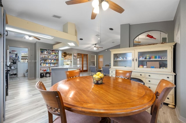 dining space with ceiling fan, lofted ceiling, and light wood-type flooring