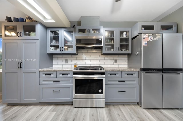 kitchen featuring appliances with stainless steel finishes, gray cabinetry, and light stone counters