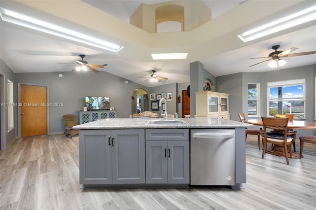 kitchen featuring an island with sink, sink, gray cabinetry, stainless steel dishwasher, and light hardwood / wood-style flooring