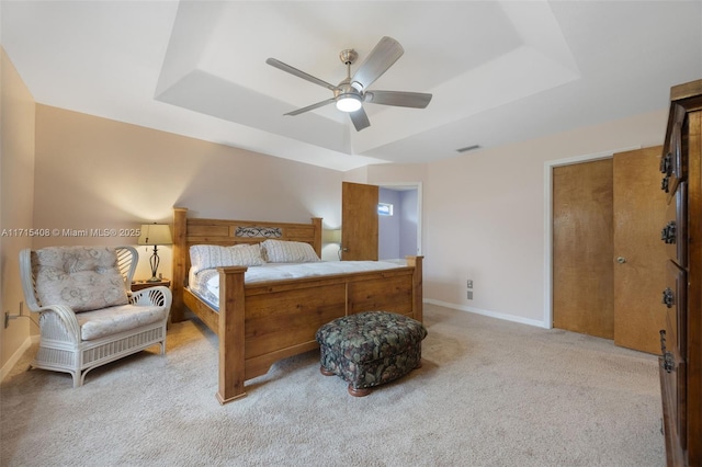 carpeted bedroom featuring a tray ceiling and ceiling fan