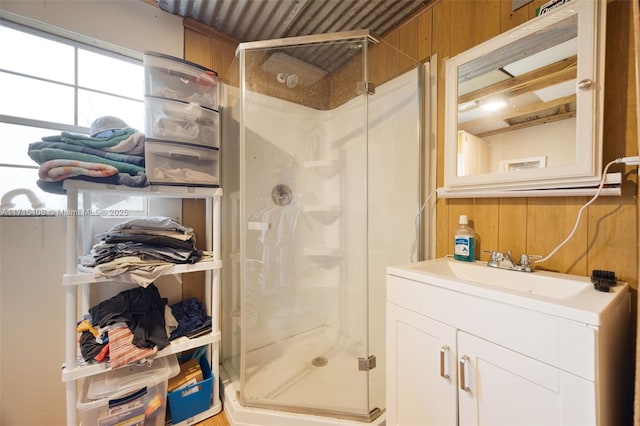 bathroom with a shower with door, vanity, and wood walls