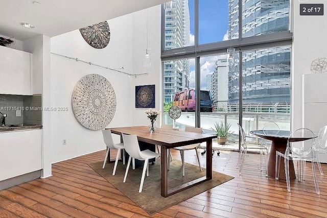 dining room with expansive windows, wood-type flooring, and a towering ceiling