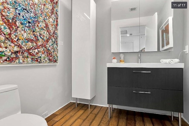 bathroom with visible vents, vanity, toilet, and wood finished floors