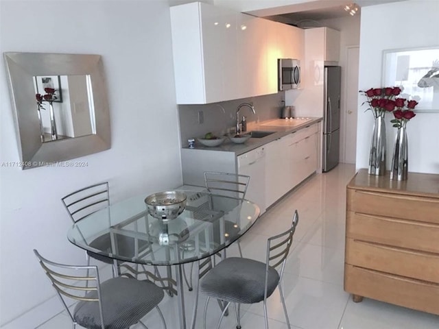 kitchen featuring white cabinetry, sink, light tile patterned floors, and appliances with stainless steel finishes