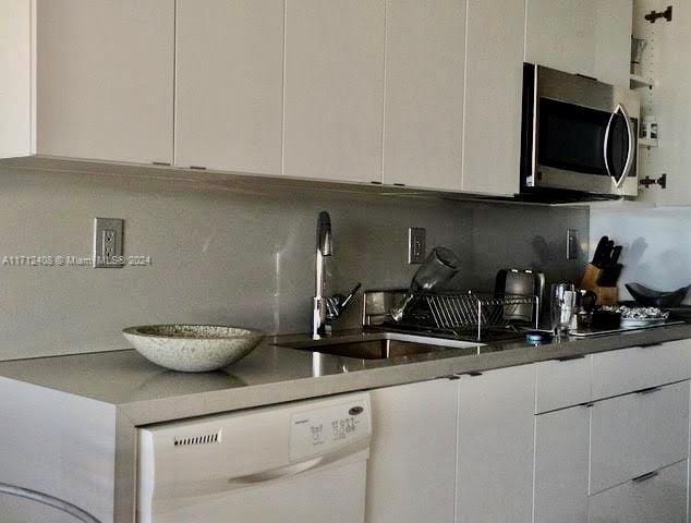 kitchen with white cabinetry, decorative backsplash, sink, and white dishwasher