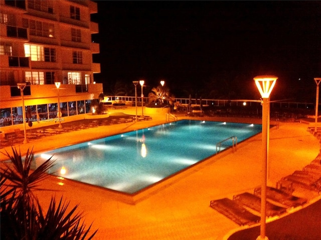 view of pool at twilight