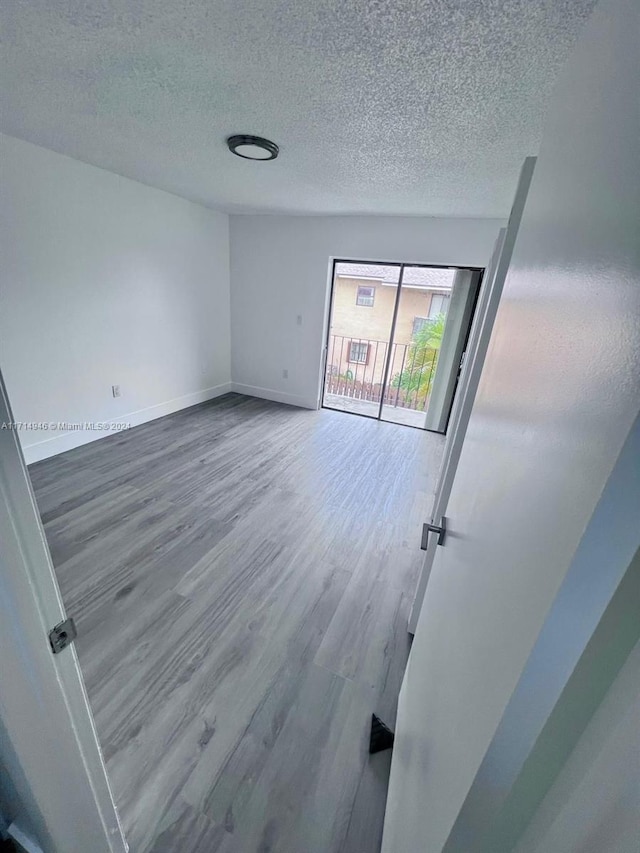 empty room with hardwood / wood-style flooring and a textured ceiling