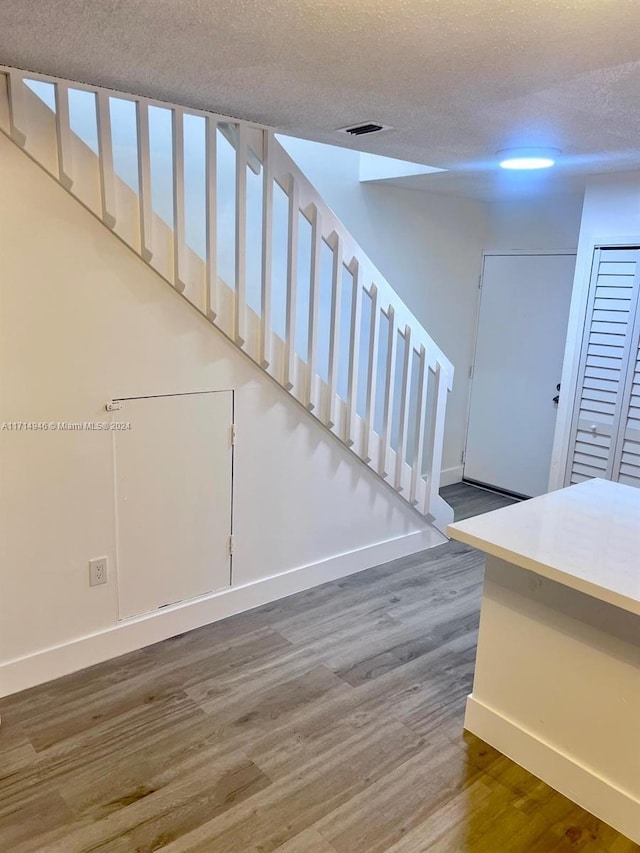 staircase featuring wood-type flooring and a textured ceiling