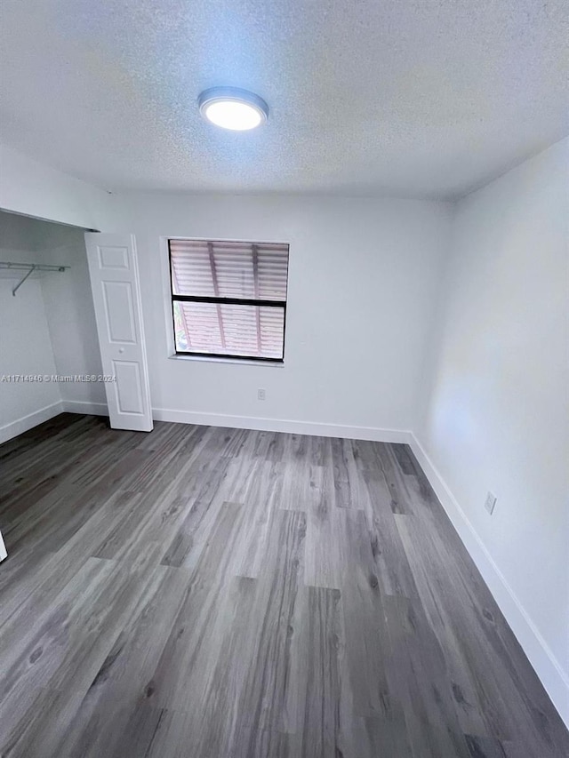 unfurnished bedroom with a textured ceiling, a closet, and dark hardwood / wood-style floors