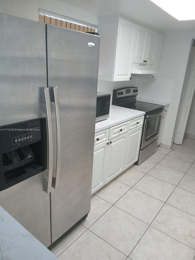 kitchen featuring appliances with stainless steel finishes, light tile patterned floors, and white cabinetry