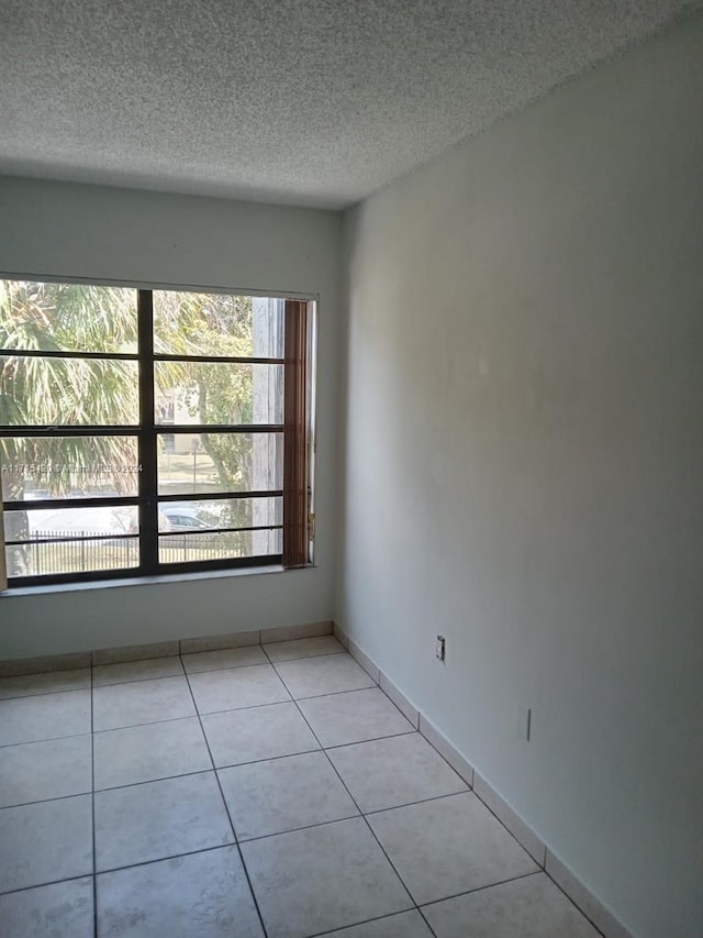 tiled empty room with a textured ceiling