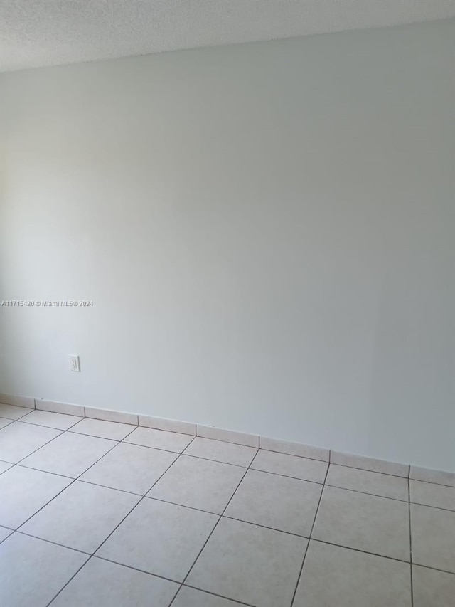 tiled empty room with a textured ceiling